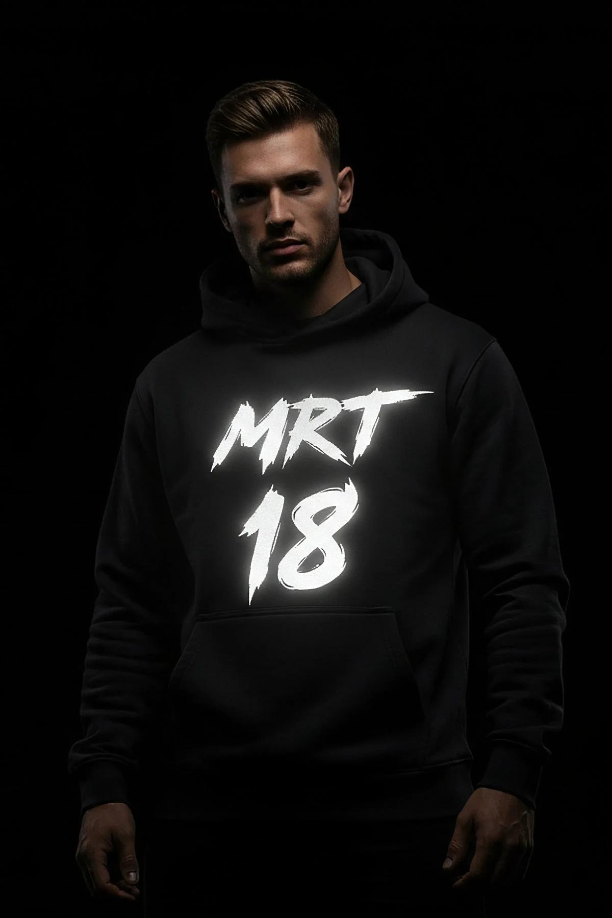 Erkek modelde flaş ışığında beyaz parlayan büyük MRT 18 fırça darbesi grafikli reflektör siyah kapüşonlu sweatshirt