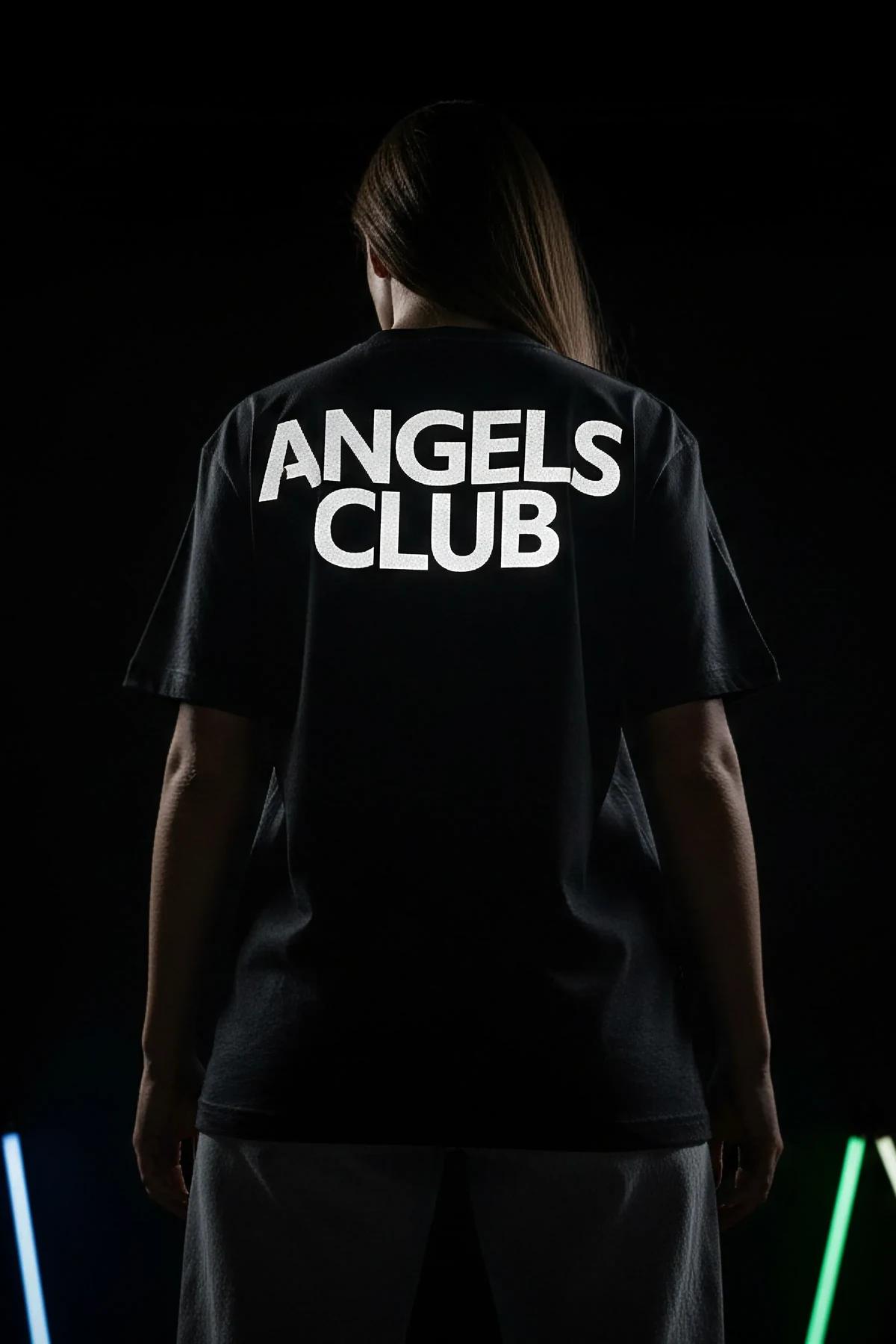 Düz paça koyu kot ve beyaz spor ayakkabıyla kombin edilmiş siyah oversize Angels Club reflektör tişört