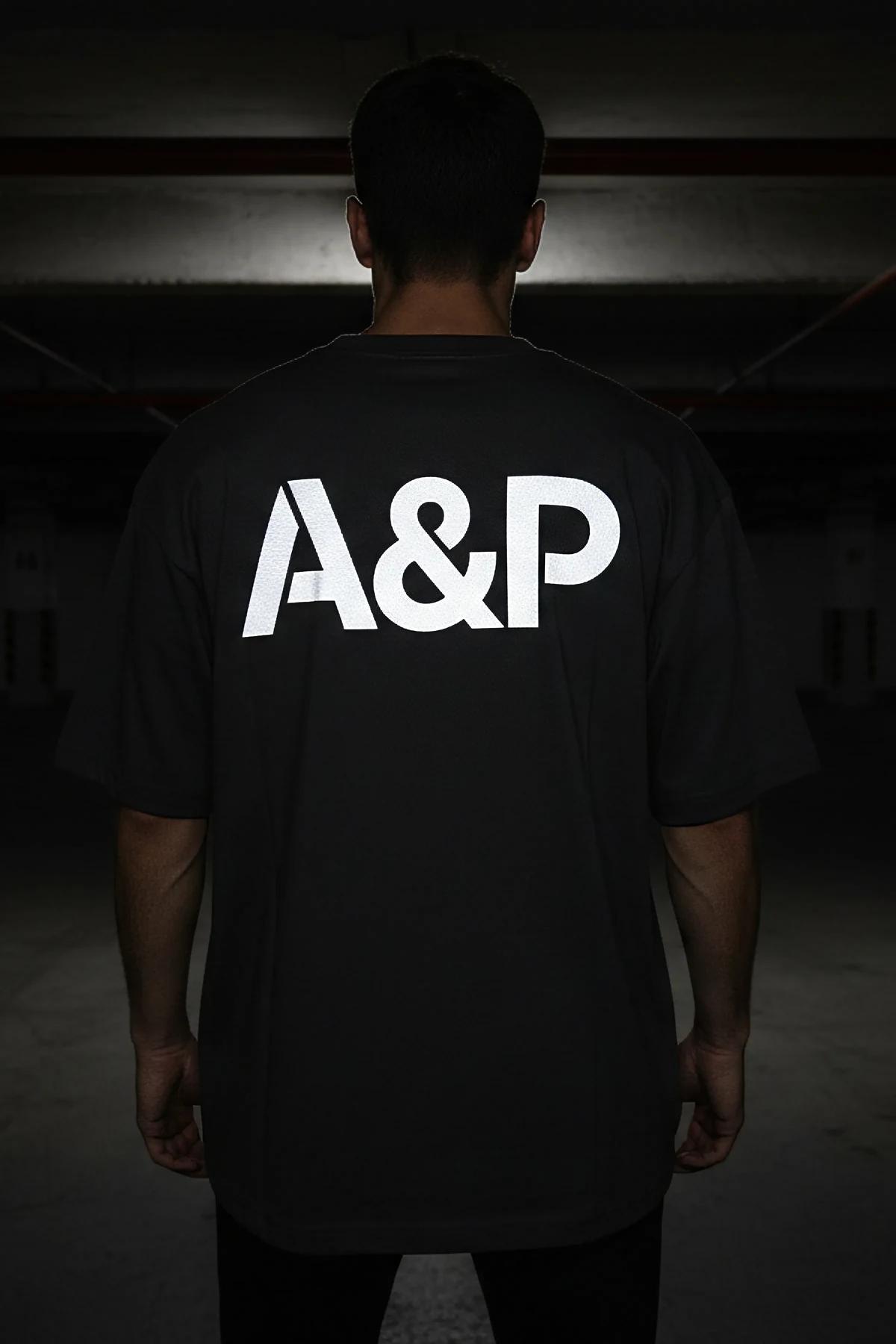 Büyük beyaz reflektör A&P logo baskılı düşük omuz sokak stili siyah oversize pamuklu tişörtün arka görünümü