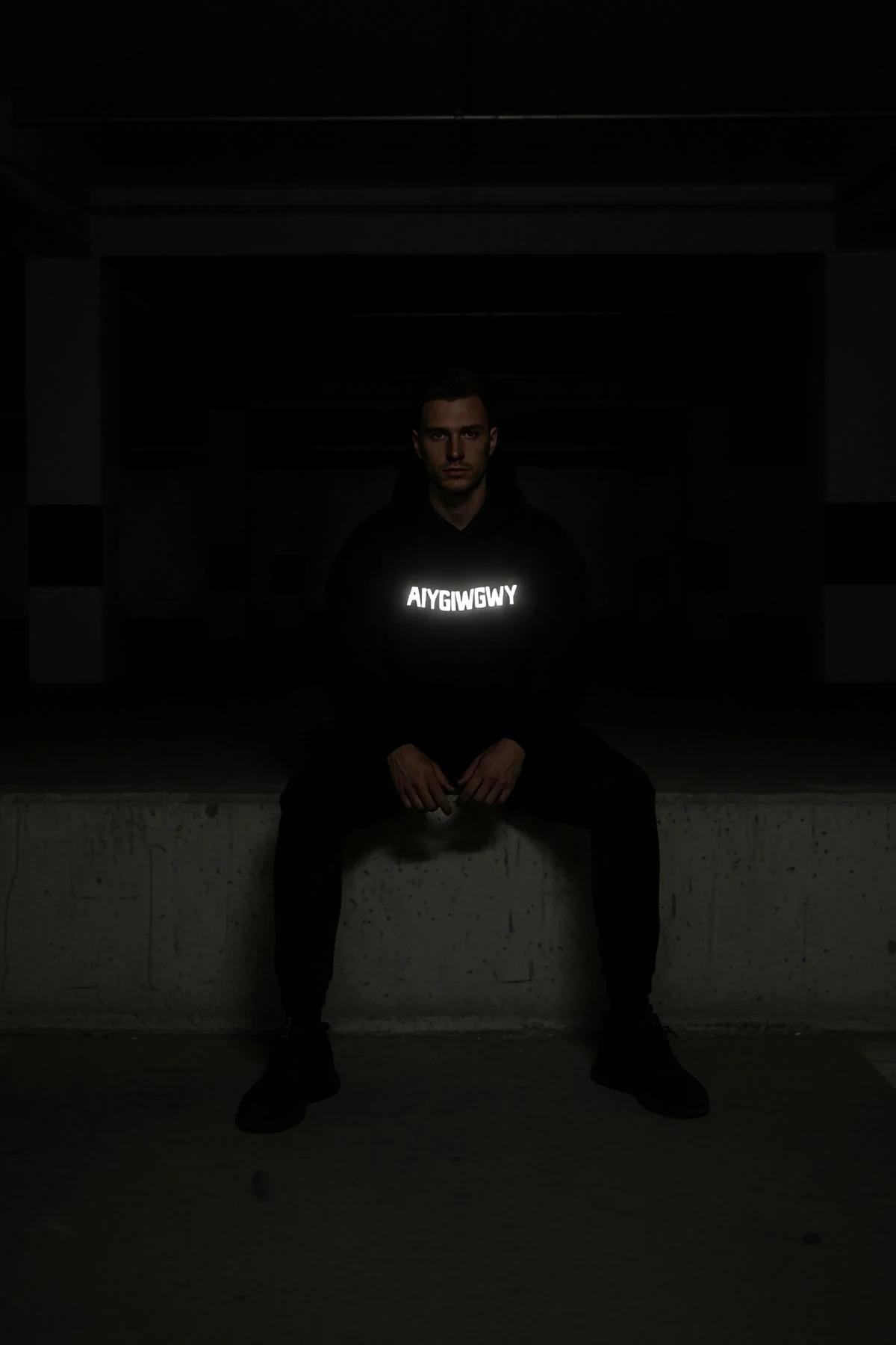 Siyah kapüşonlu sweatshirt ön baskı detayı gece ışığında yansıma