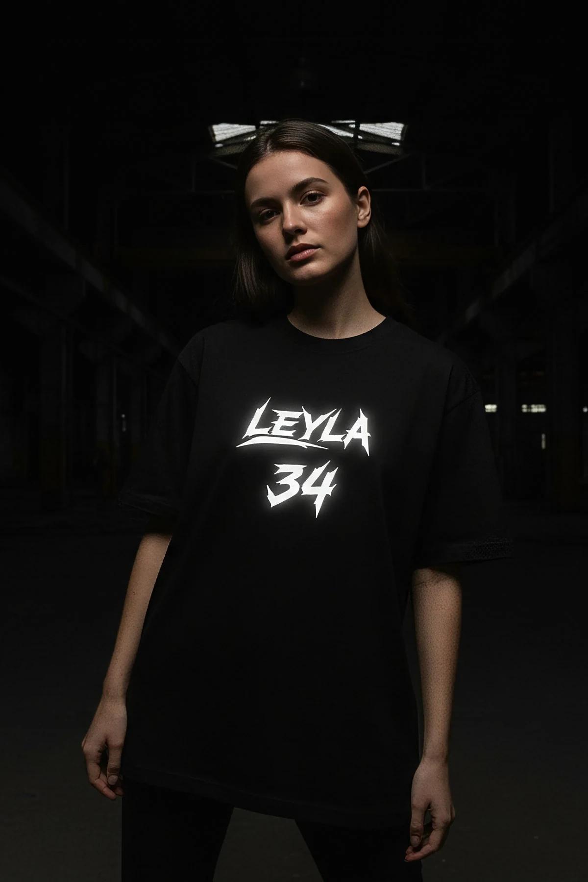 Siyah pamuklu oversize tişört göğsündeki beyaz grunge tarzı serigrafi grafik baskısının yakın çekimi