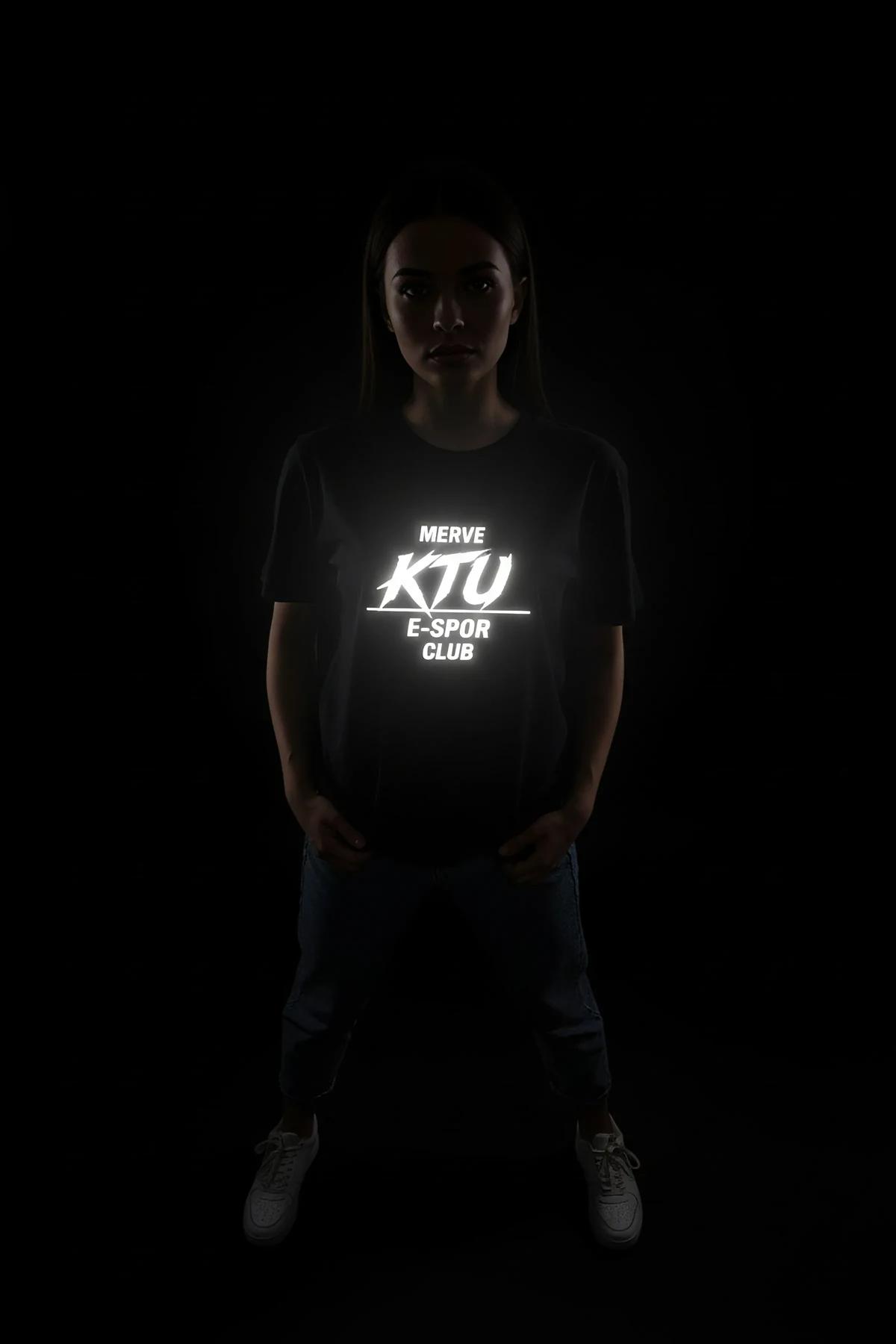 Tam göğüs parıltı efektini gösteren karanlıkta fotoğraflanan beyaz parlayan logo baskılı siyah reflektör tişört