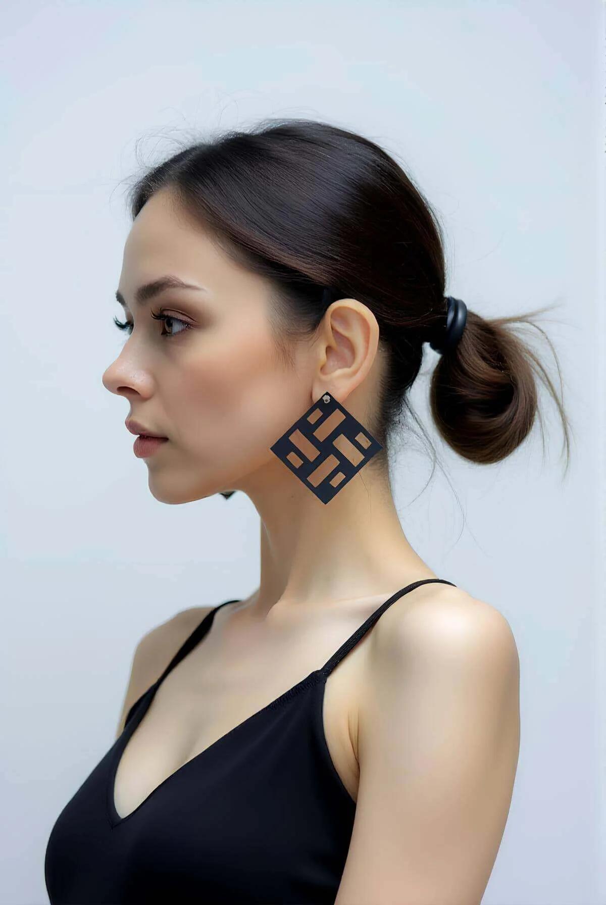Mat siyah lazer kesim geometrik kare küpe, dikdörtgen kesim slot deseni, modelin kulağında, yan profil