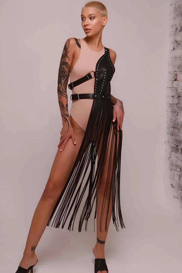 ten rengi bodysuit üzerine giyilen siyah suni deri asimetrik püsküllü harness etek, gümüş zımba süsleme ve yan toka