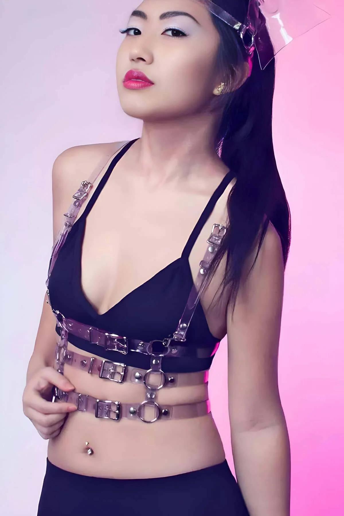 Siyah bralet üzerinde üç yatay bant, gümüş O-halka donanımı ve toka kapamalarla şeffaf berrak PVC göğüs harness