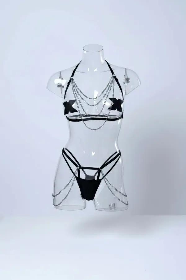 Manken üzerinde X-kap halter sütyen, dökümlü gümüş zincirler ve bantlı tangayla siyah suni deri harness seti