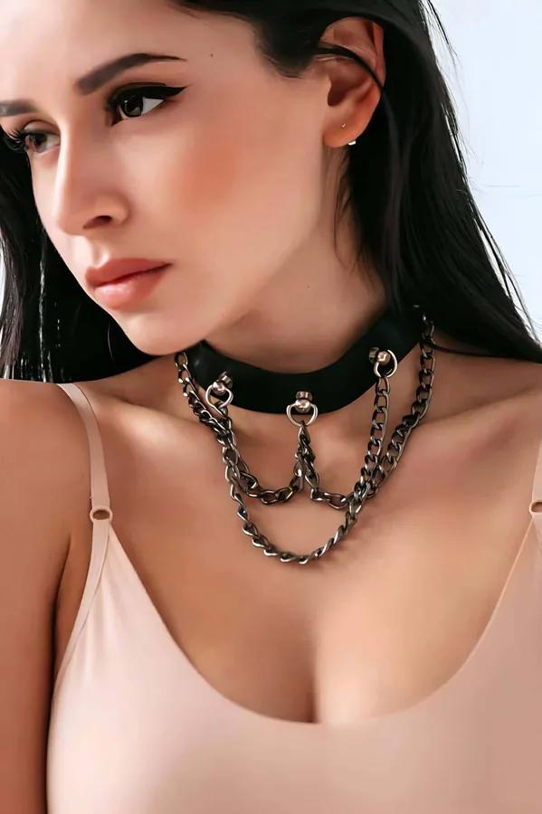 Modelde üç sarkıtılmış koyu metal zincir ve O-halka donanımlı siyah suni deri geniş bantlı çoker