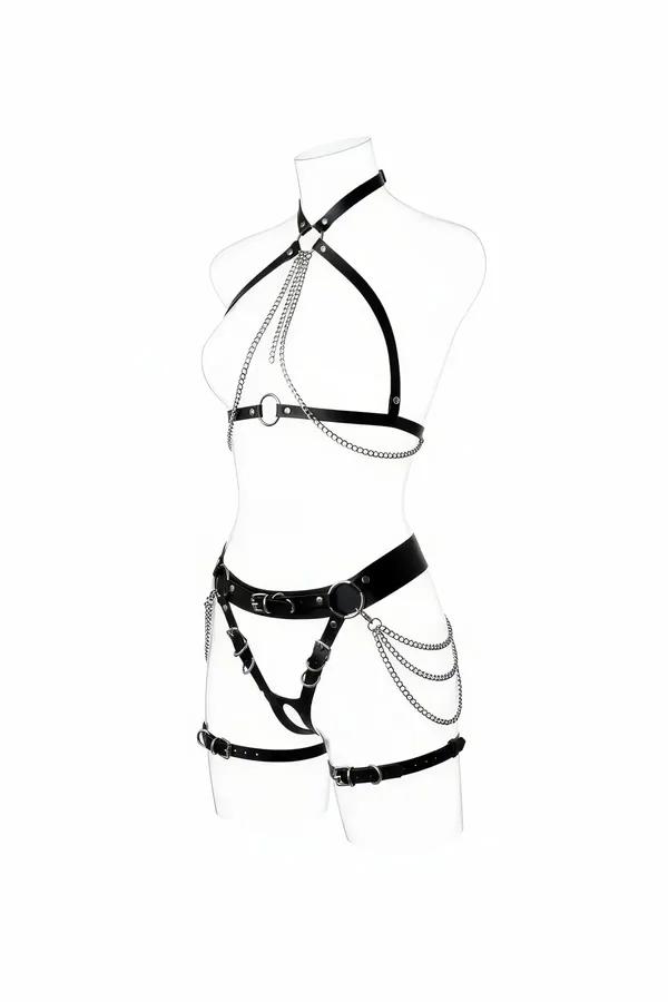 Beyaz manken üzerinde katmanlı gümüş zincir göğüs dökümlü ve asimetrik uyluk bantlı siyah suni deri tam vücut harness