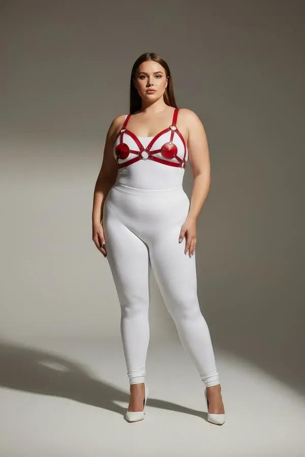 Kalp şekilli bardak çerçeveli ve altın O-halka aksesuarlı kırmızı bantlı suni deri göğüs harness, beyaz bodysuit üzerinde