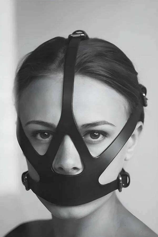 Geometrik bant kesimler ve gümüş O-halka kapamalarla siyah suni deri yüz maskesi harness ön görünüm