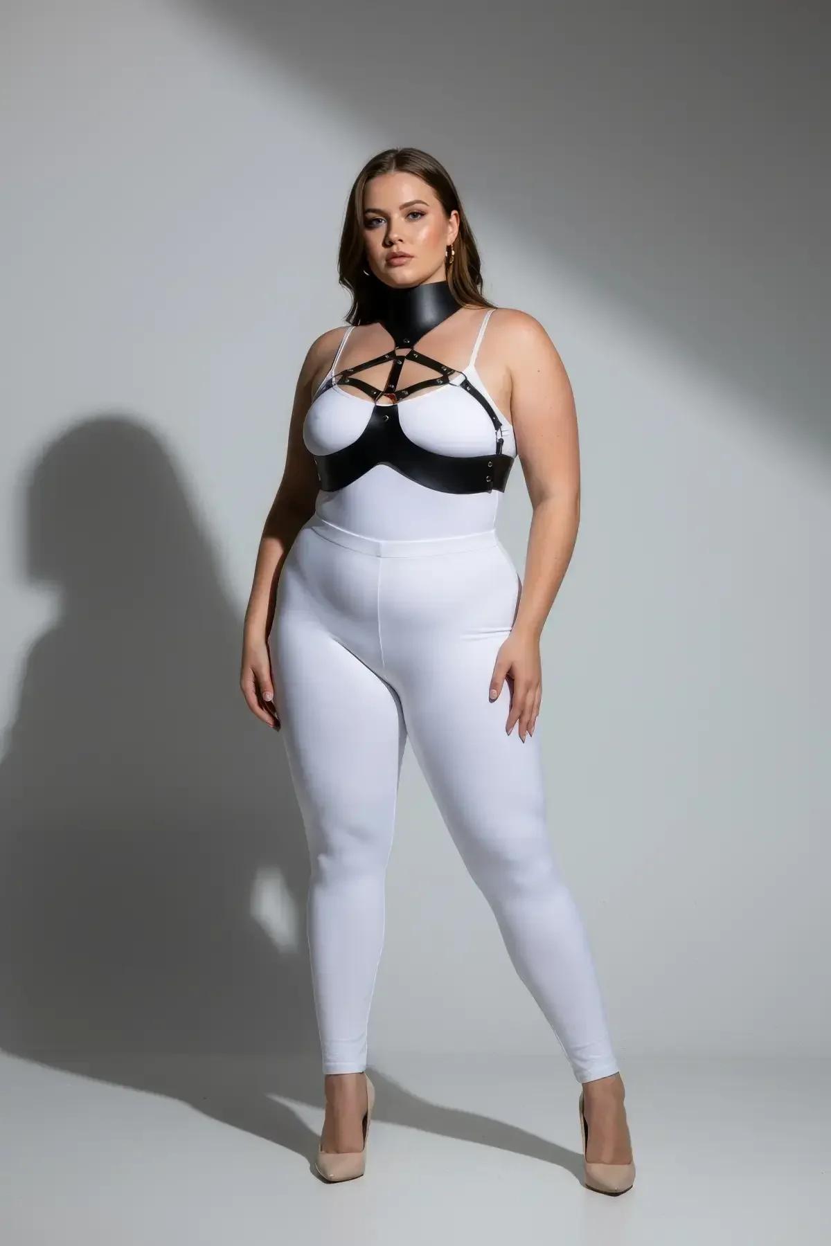 Beyaz body üzerine giyilmiş yapılandırılmış yüksek boyunluk ve gümüş O-halkalı siyah suni deri göğüs harness