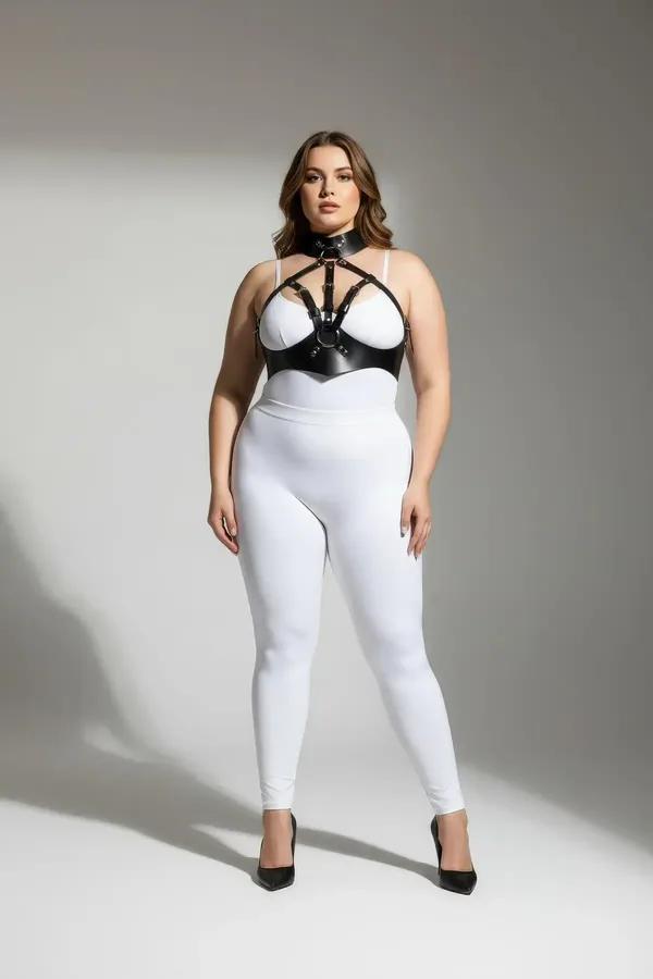 Artı beden modelde beyaz sütyen ve tayt üzerine giyilmiş yüksek çoker boyunluk ve gümüş O-halkalı siyah suni deri vücut harness