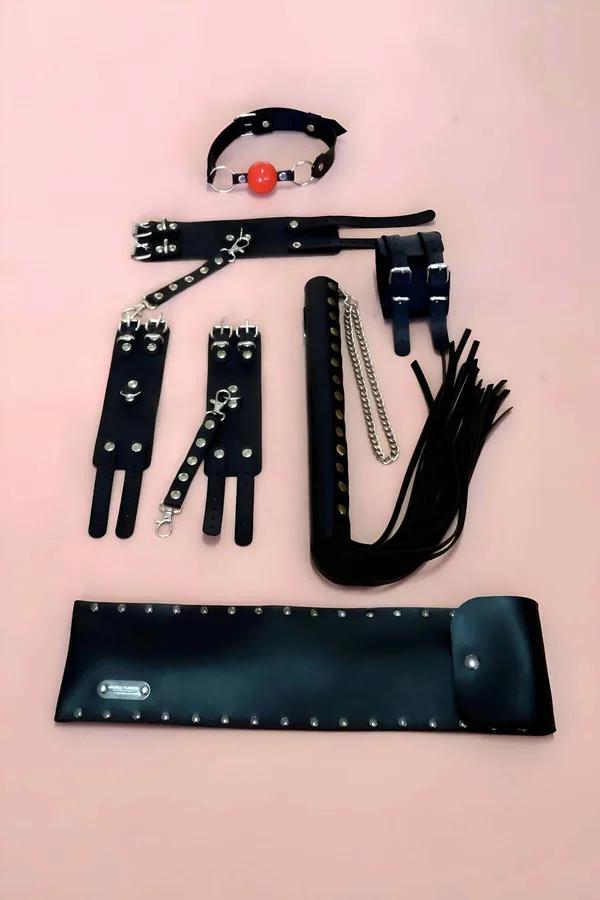 Pembe arka fonda zımbalamalı bilek kelepçeleri, kırmızı top gag, flogger kırbaç ve saklama keseli siyah suni deri 5 parça kısıtlama aksesuar seti