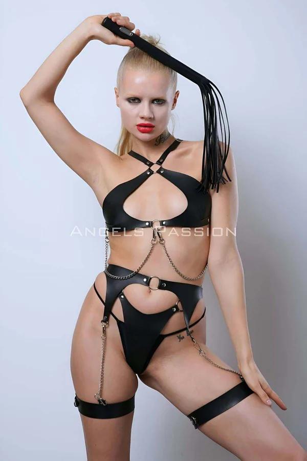 Modelde açık kup göğüs, altın tonlu O-halkalar, zincir halkalar ve uyluk jartiyer askılı siyah suni deri tam vücut harness