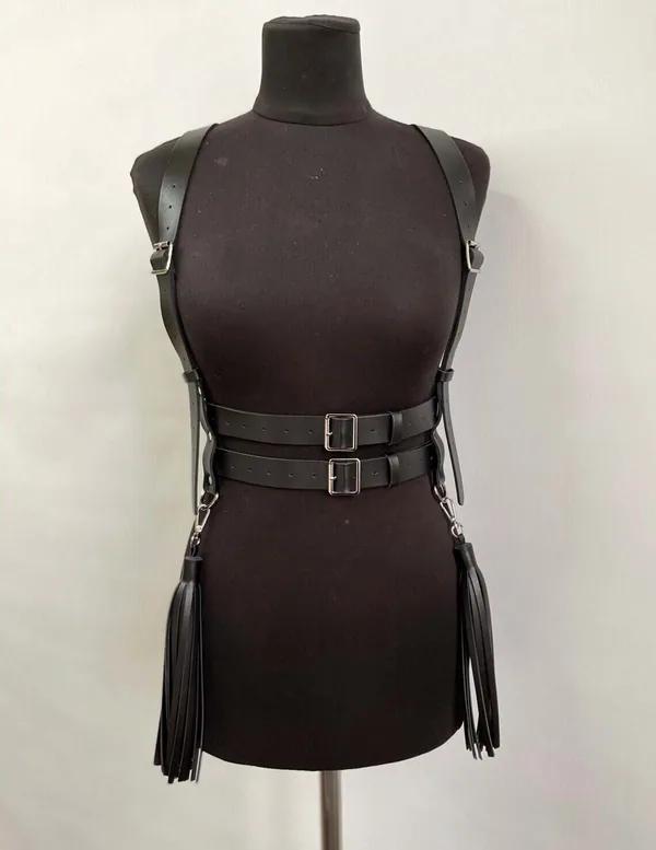 Gümüş D-halkalardan sarkan çift bel kemerleri ve uzun saçak püsküllerle siyah suni deri askılı vücut harness