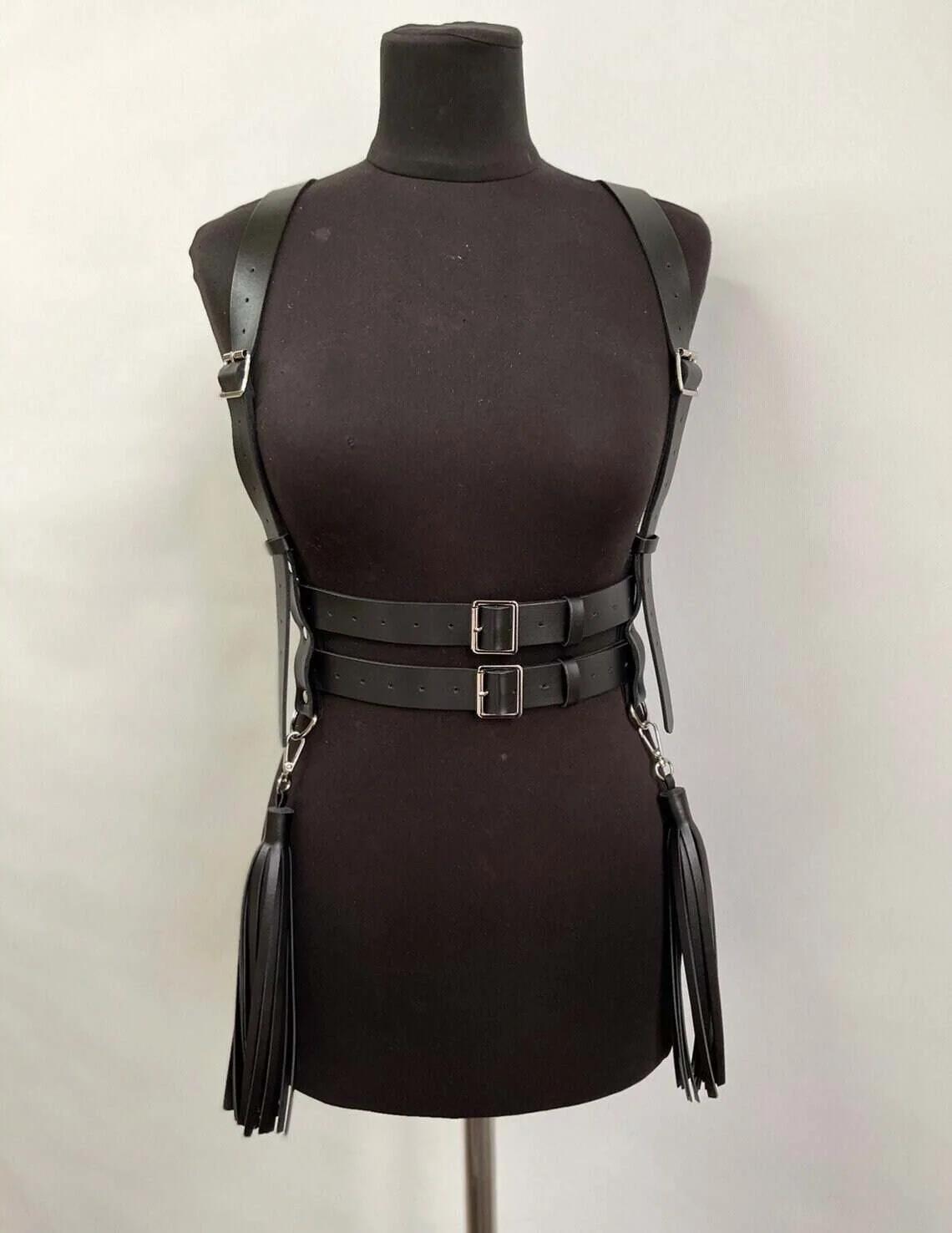 Gümüş D-halkalardan sarkan çift bel kemerleri ve uzun saçak püsküllerle siyah suni deri askılı vücut harness