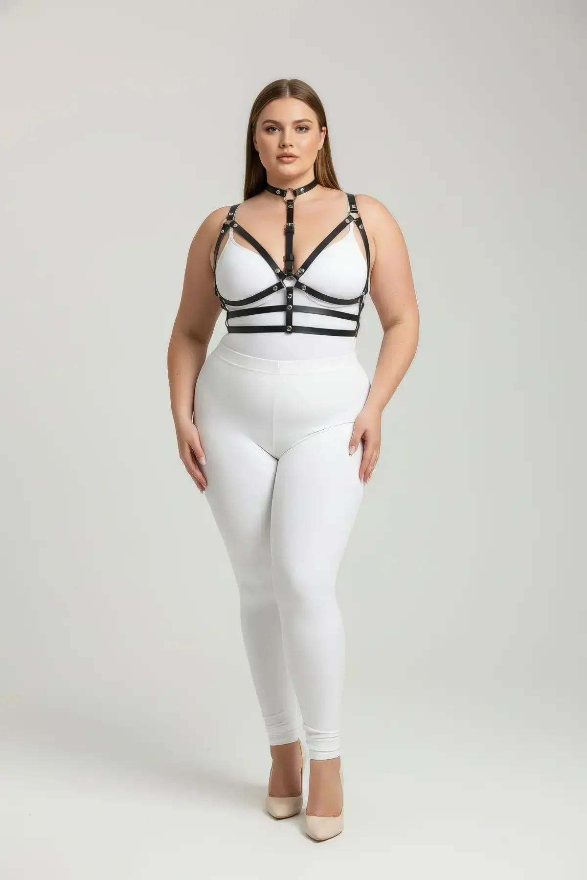 Beyaz bodysuit üzerine giyilen gümüş O-halka merkezli siyah suni deri bantlı çoker göğüs harness