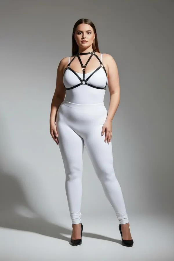 Beyaz bodysuit üzerinde altın O-halka detaylı siyah suni deri bantlı vücut harness, üçgen göğüs bant konfigürasyonu