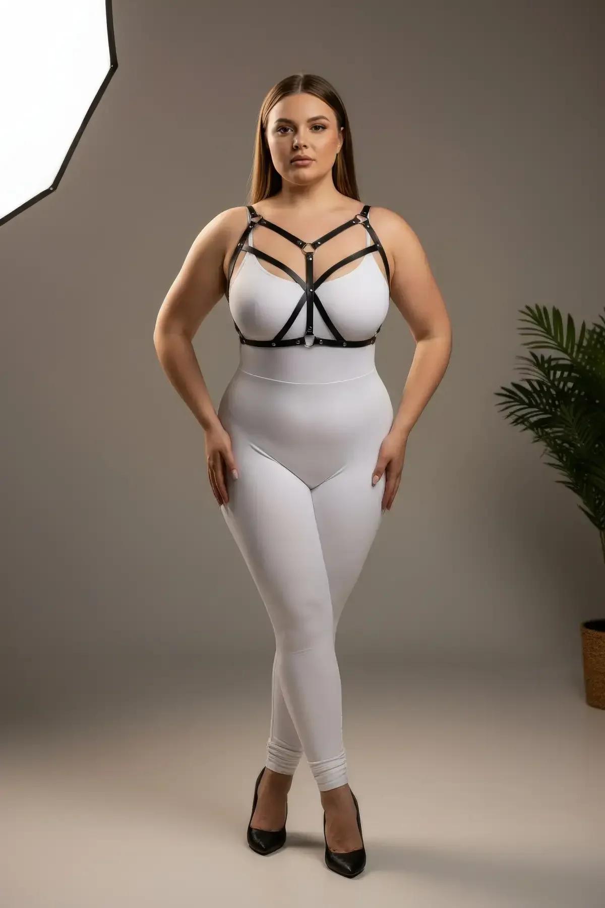 Beyaz bodysuit üzerinde artı beden model, gümüş O-halka konnektörlü siyah suni deri bantlı göğüs harness