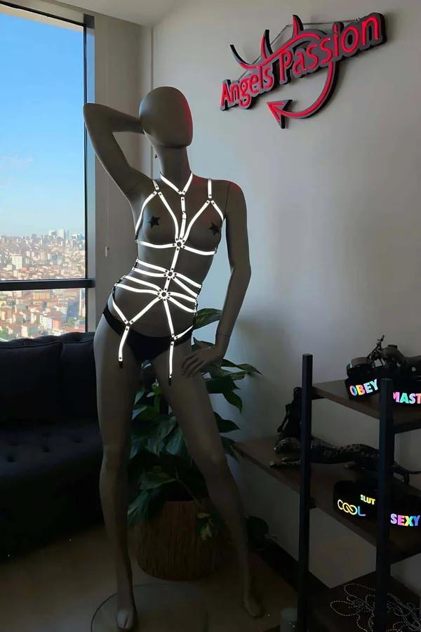 Manken üzerinde beyaz parlayan kafes askılar ve gümüş O-halka konektörlerle siyah reflektör vücut harness