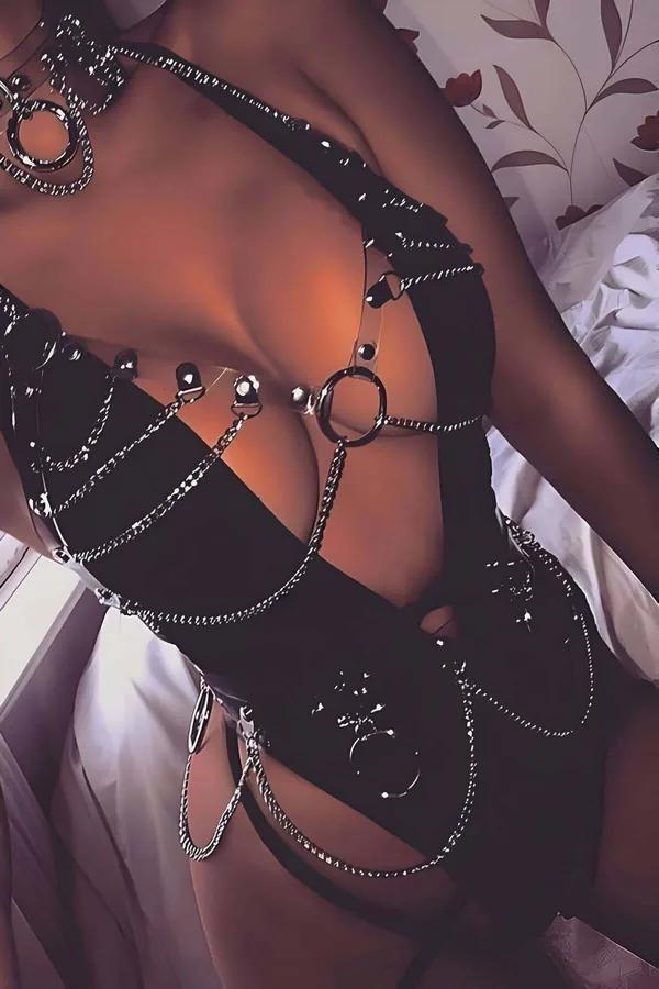 Sarkıtılmış gümüş zincirler, O-halkalar ve göğüsten bele şeffaf PVC bantlarla siyah suni deri tam vücut harness