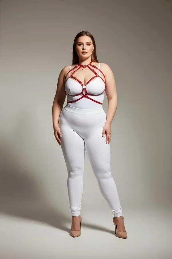 Dolgun modelde beyaz bodysuit üzerinde altın O-halkalı kırmızı suni deri kafes harness sütyen