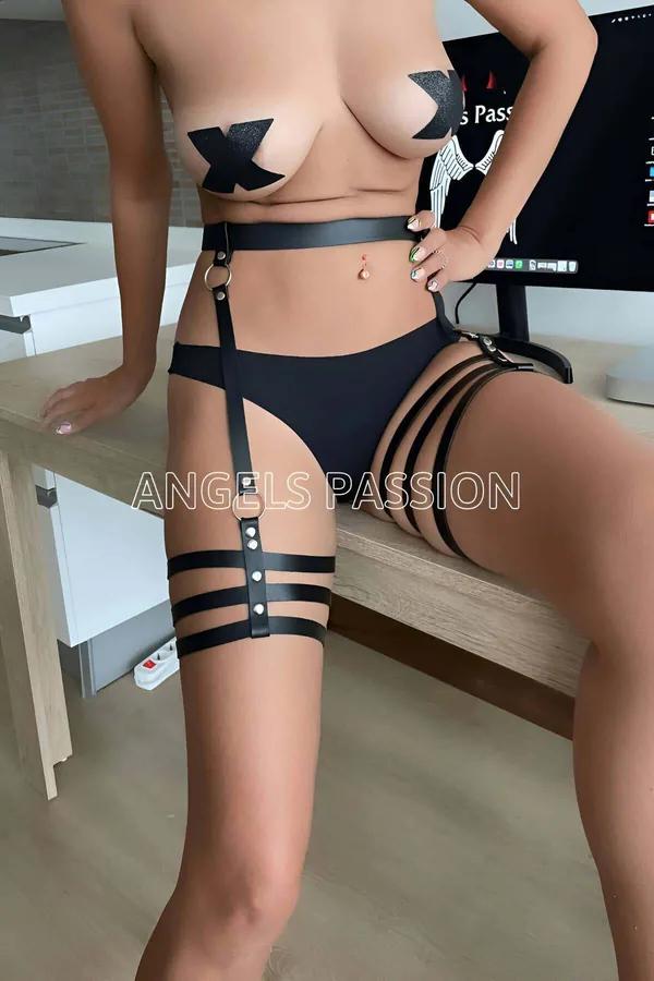 Kadın modelde kalçada gümüş O-halka ve üçlü bantlı uyluk kelepçeli siyah suni deri jartiyer harness