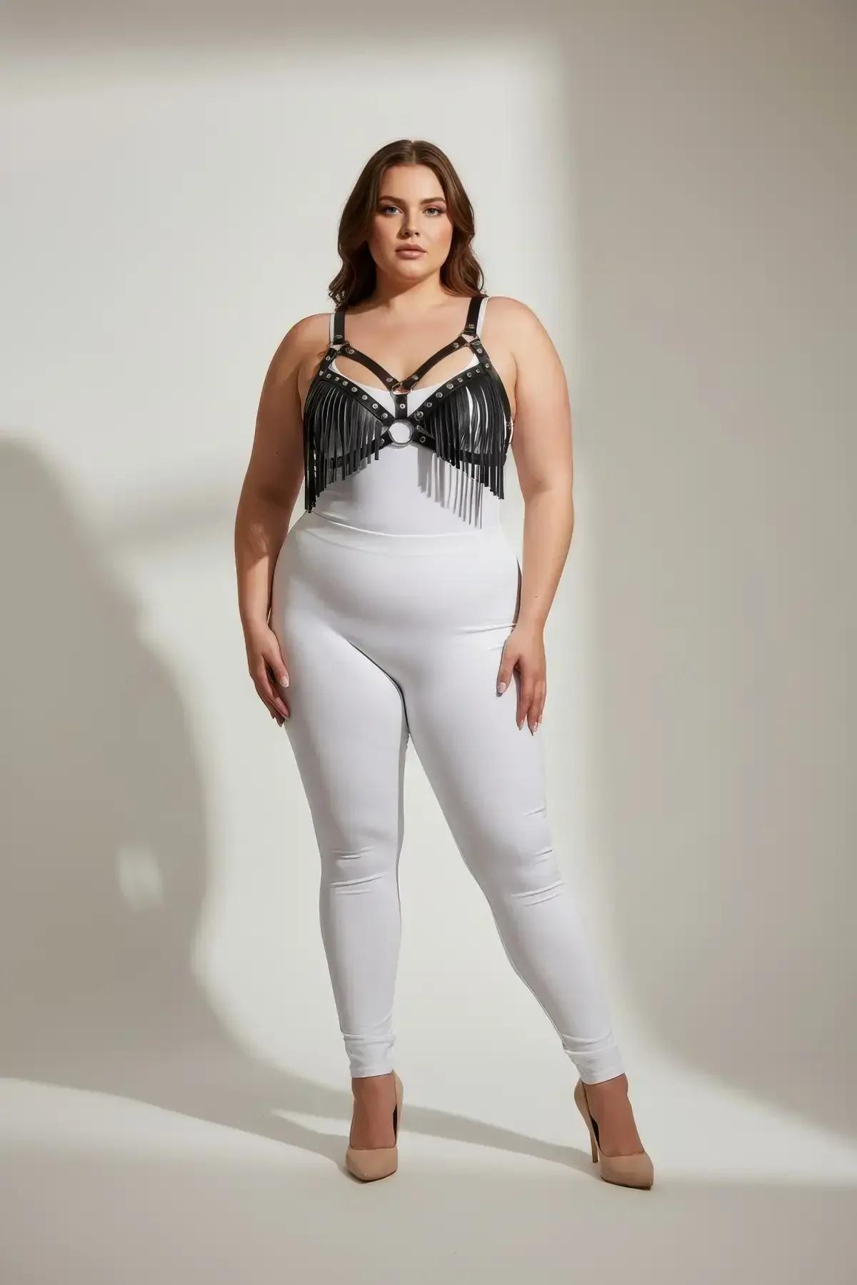 Beyaz bodysuit üzerinde gümüş O-halka ve perçin zımbalı siyah suni deri püsküllü göğüs harness