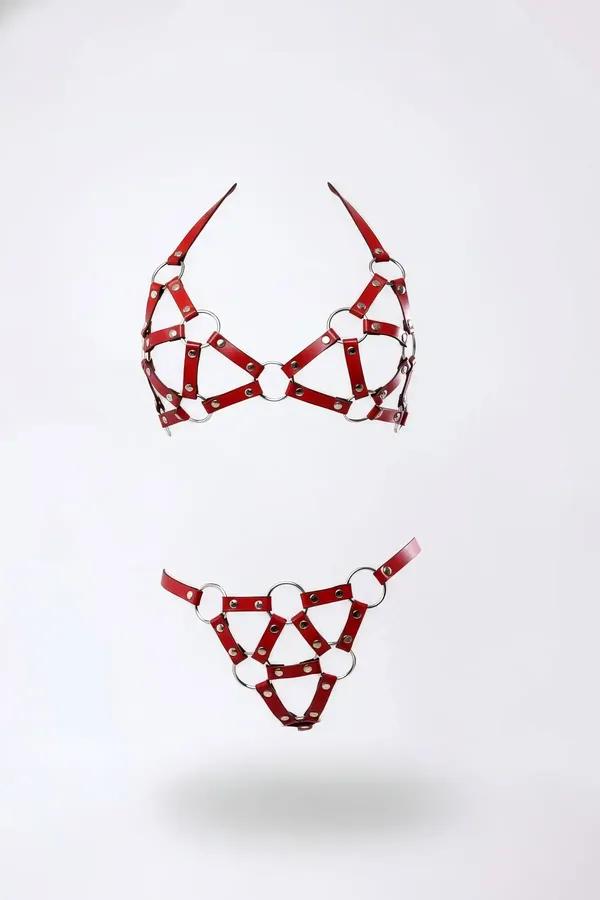 Beyaz arka planda gümüş O-halkalar ve kubbe perçinli kırmızı suni deri kafesli sütyen ve G-string harness seti