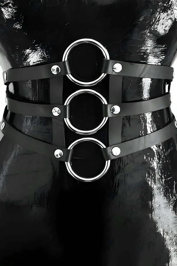 Kadın gövdesinde üç üst üste gümüş O-halkalar ve kubbe perçinlerle siyah suni deri bel harness