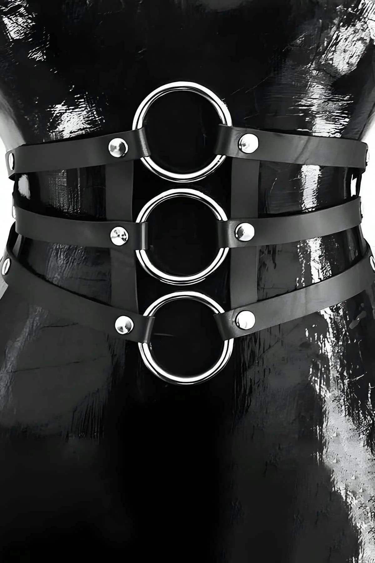 Kadın gövdesinde üç üst üste gümüş O-halkalar ve kubbe perçinlerle siyah suni deri bel harness