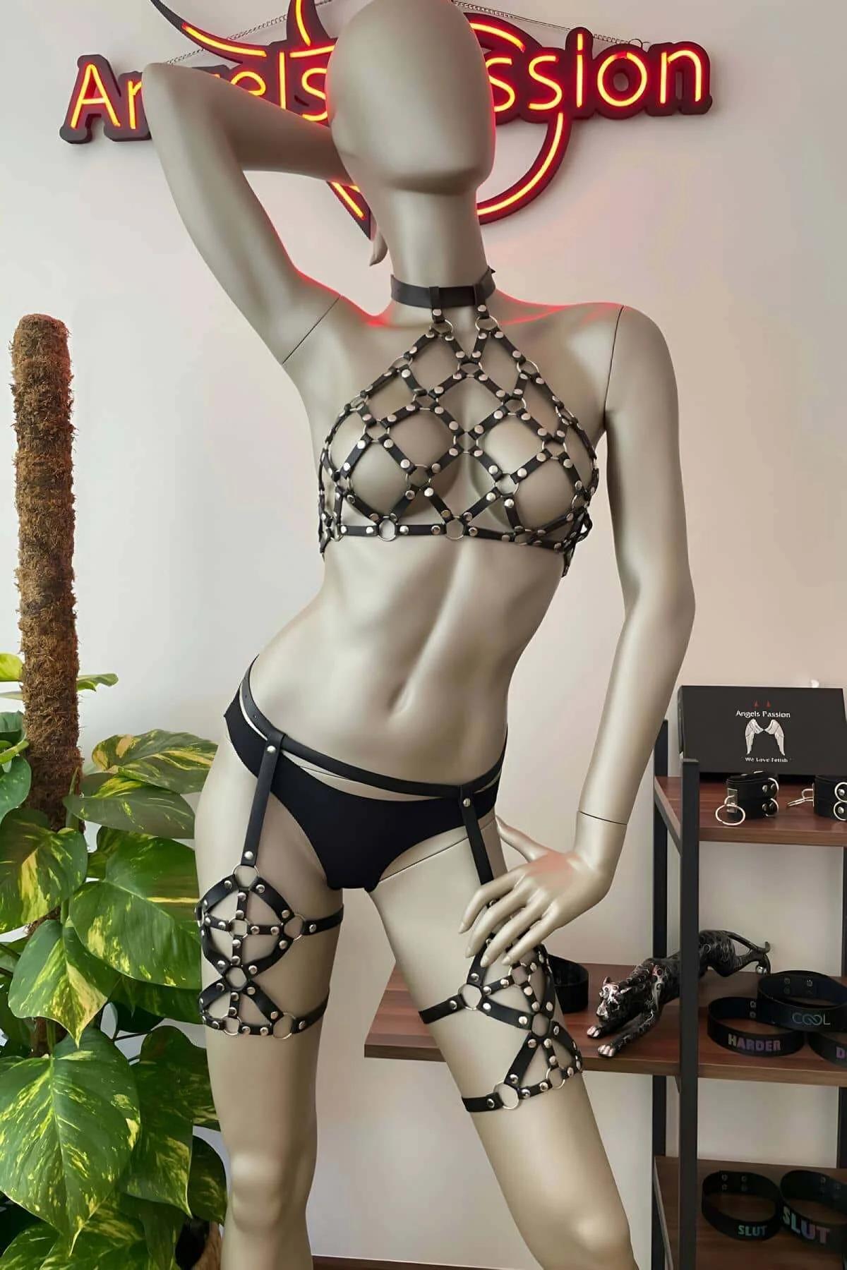 Manken üzerinde gümüş kubbe perçinli ve eşleşen uyluk jartiyer bantlı siyah suni deri zımbalı kafes halter harness