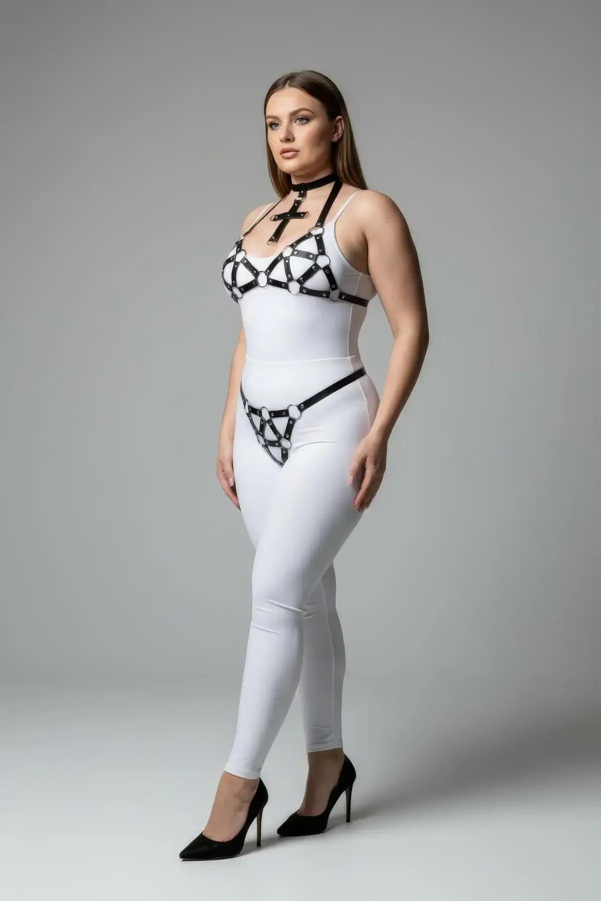 Çapraz çoker, geometrik gümüş O-halka göğüs harness ve kalça G-string içeren siyah suni deri 3 parçalı harness takımı, beyaz üzerinde