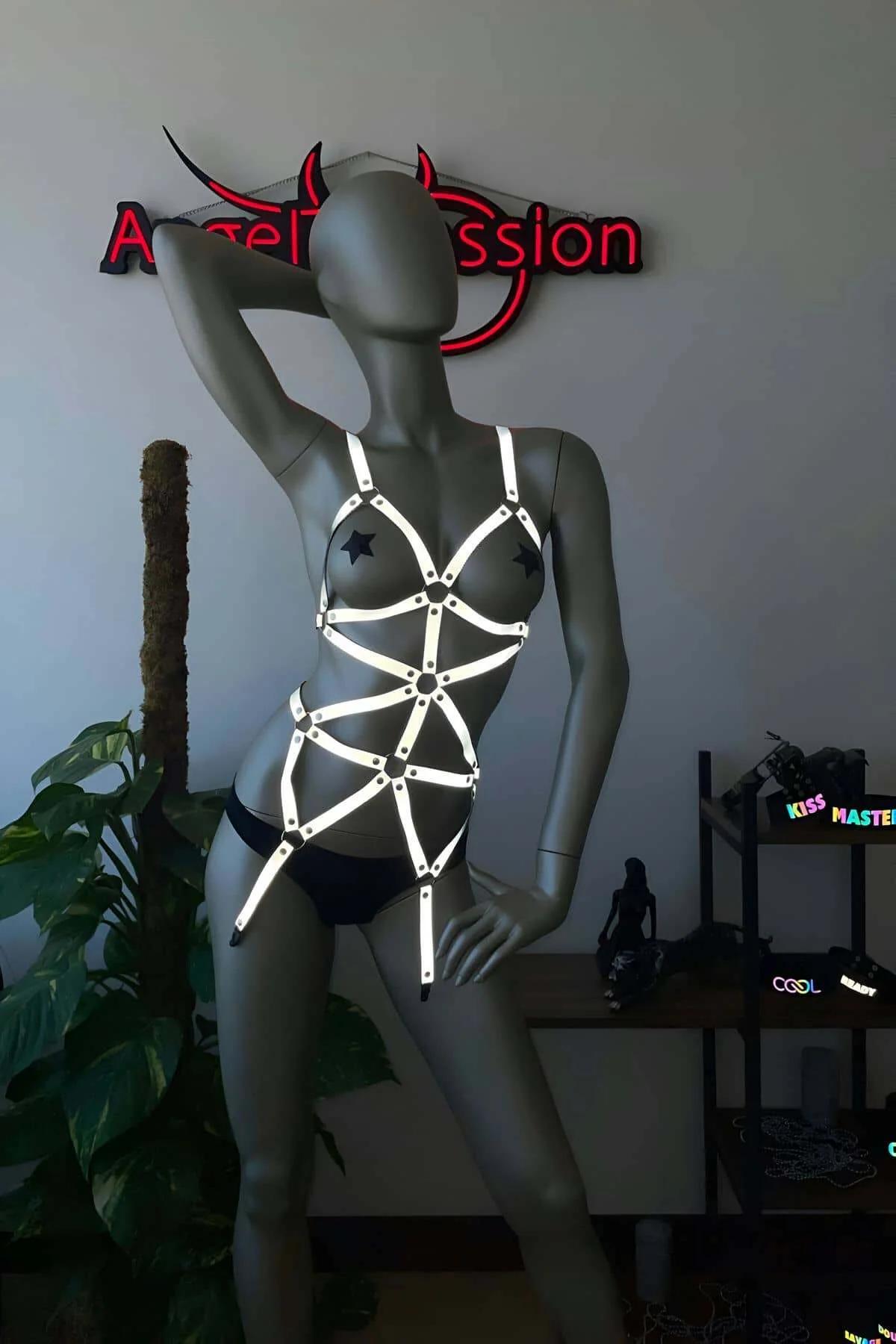 Az ışıklı ortamda göğüsten kalçaya geometrik kaplama gösteren çıplak ten üzerinde giyilen reflektör tam vücut harness