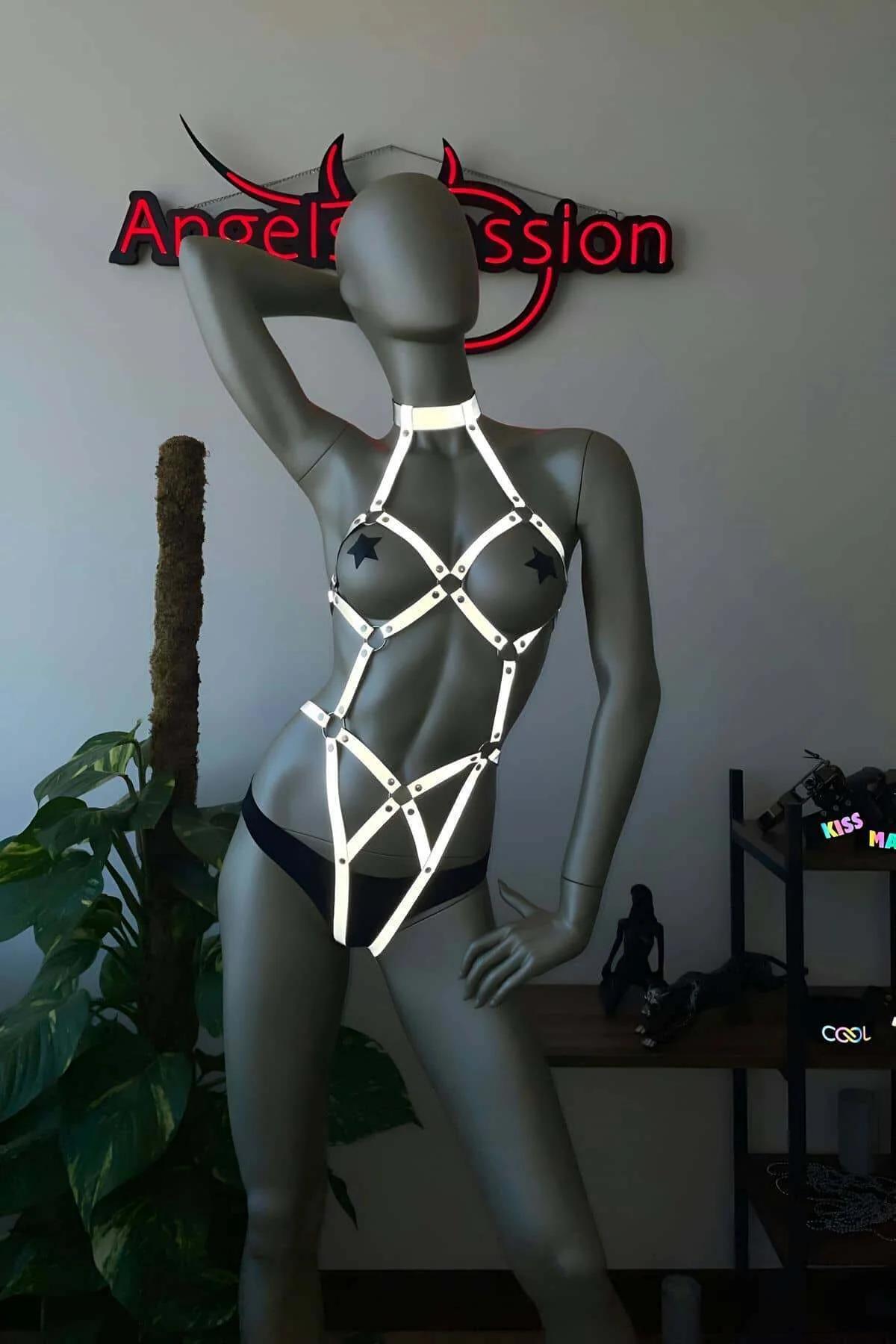 Gri manken üzerinde yıldız şekilli gümüş donanımlı beyaz reflektör tam vücut harness, boyundan başlayan geometrik kafes strap tasarımı