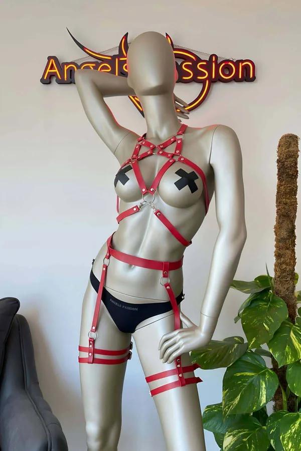 Manken üzerinde yıldız göğüs detaylı, gümüş O-halkalı, çift uyluk askılı ve baldır bantlı kırmızı suni deri tam vücut harness