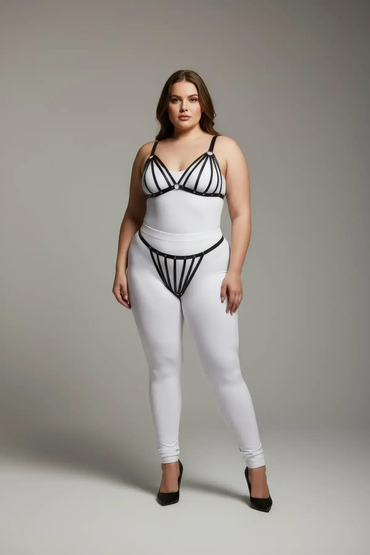 Beyaz bodysuit üzerinde gümüş O-halka aksesuarlı siyah suni deri kafes harness sütyen ve tanga takımı