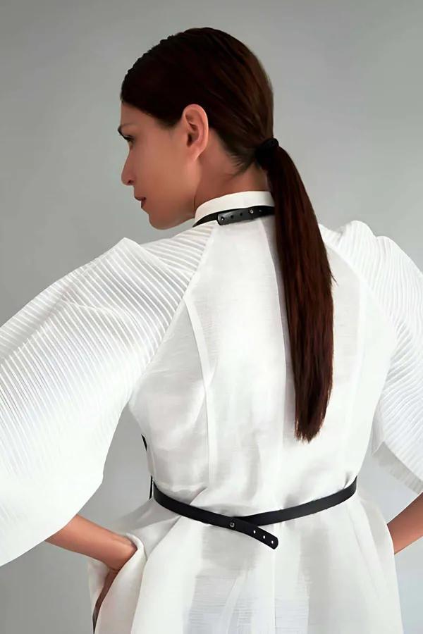 Beyaz kıyafet üzerinde ince boyunluk askısı, bel bandı ve dikey konnektörü gösteren siyah suni deri minimalist vücut harness arka görünüm