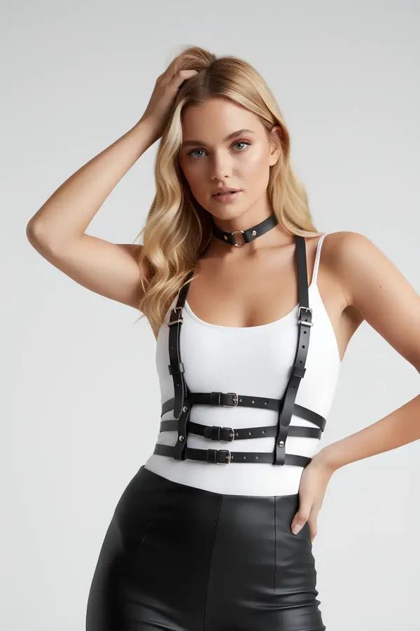 Siyah suni deri göğüs harness, üç gümüş tokalu bant ve eşleşen O-halka çoker, beyaz bodysuit üzerinde