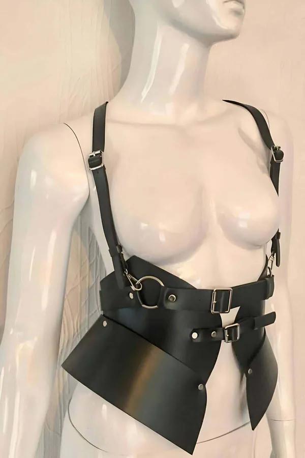 Manken üzerinde geniş bel paneli, omuz askıları ve gümüş toka donanımlı siyah suni deri asimetrik vücut harness
