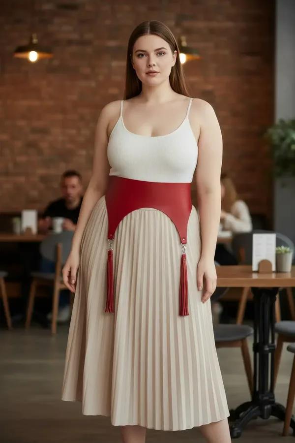 beyaz üst ve bej pileli midi etek üzerine giyilmiş çıkarılabilir püsküllü gümüş aksesuarlı kırmızı vegan deri bel harness