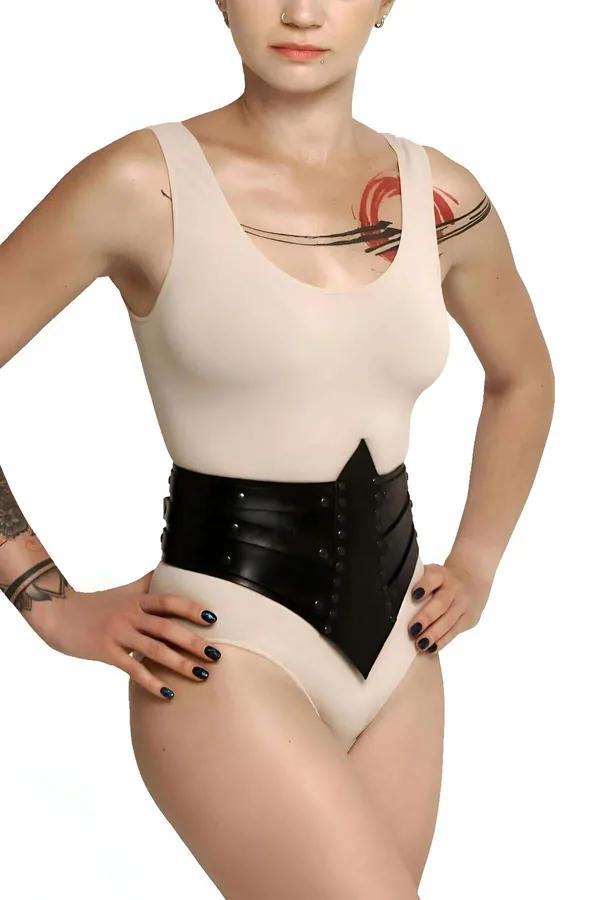 Krem rengi bodysuit üzerine giyilmiş gümüş perçin zımbalar ve çok panelli yapılandırılmış tasarımlı siyah suni deri V kesim bel korsesi
