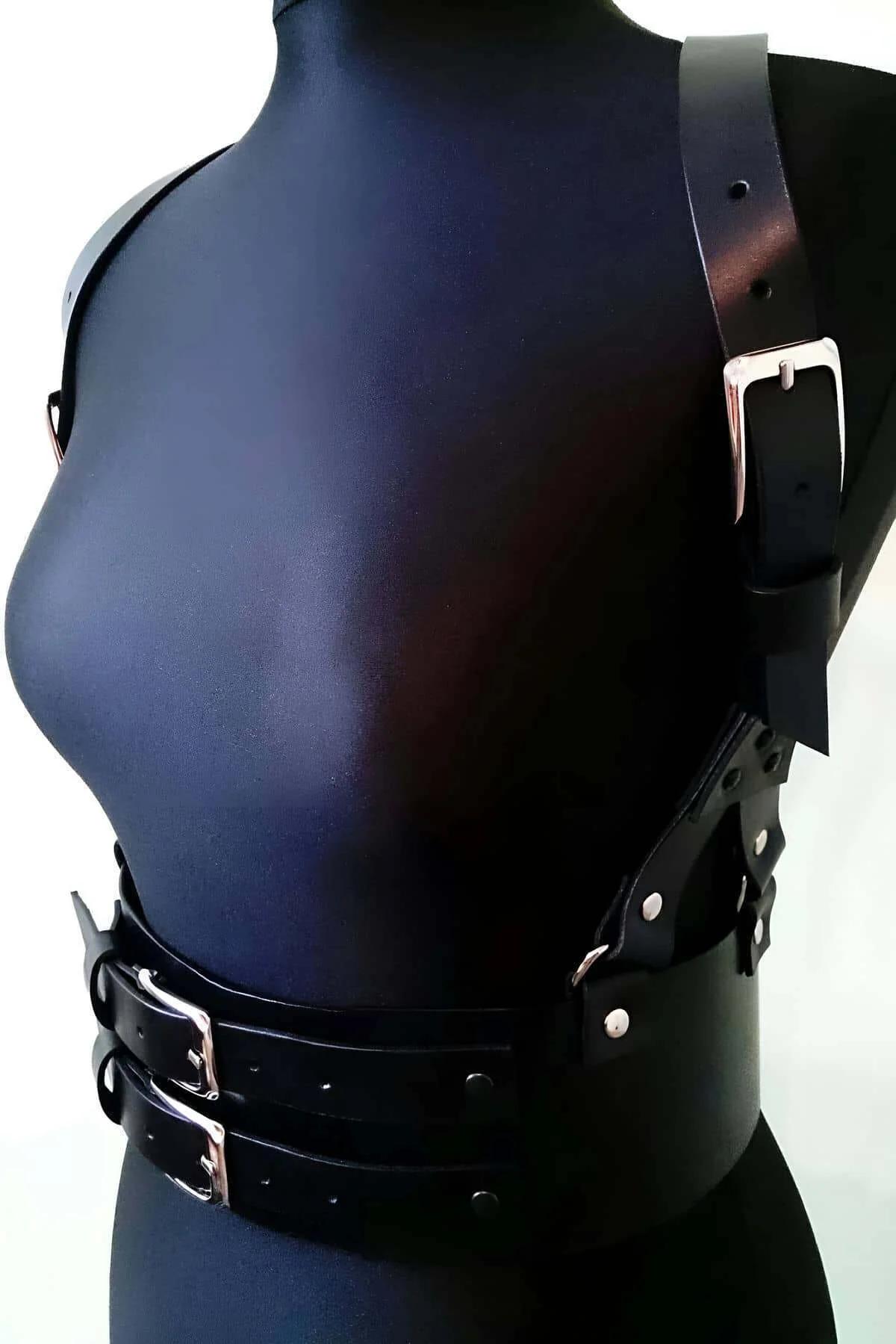Geniş çift toka bel bandı ve göğüs askı detayını gösteren siyah suni deri vücut harness kemerinin ön görünümü