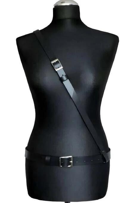Manken üzerinde tek çapraz omuz askısı ve gümüş toka bel kemeri ile minimalist siyah suni deri vücut harness