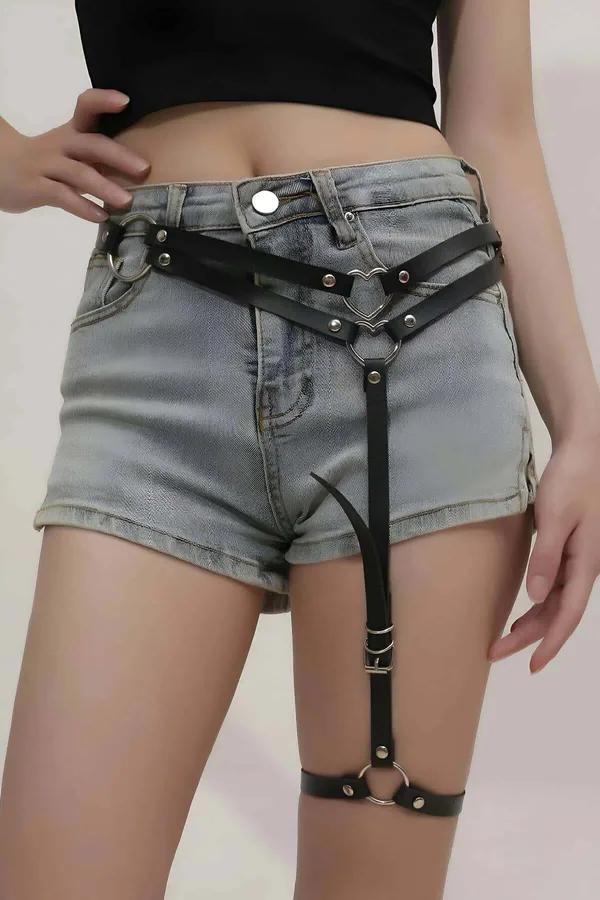 Uyluk kelepçesi görünür, denim şort üzerine giyilen gümüş kalp O-halkalı siyah suni deri tek bacak jartiyer harness