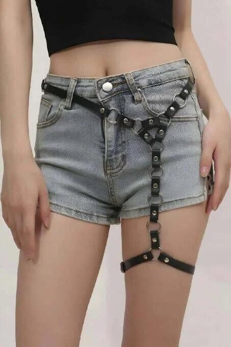 Siyah suni deri tek bacak harness askılarında gümüş O-halka ve perçin detayı, yakın çekim