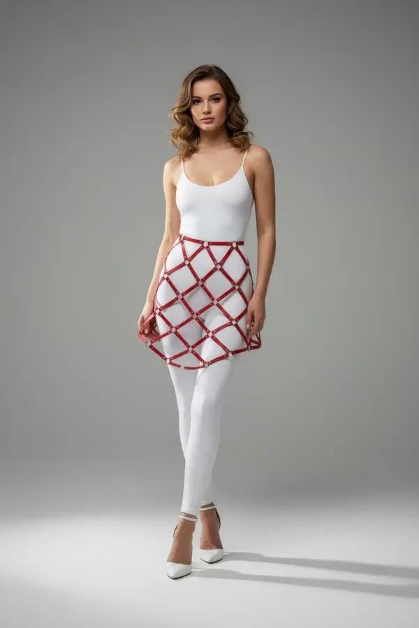 Beyaz tayt ve bodysuit üzerine giyilen gümüş çivi kesişimli kırmızı suni deri kafes etek harness