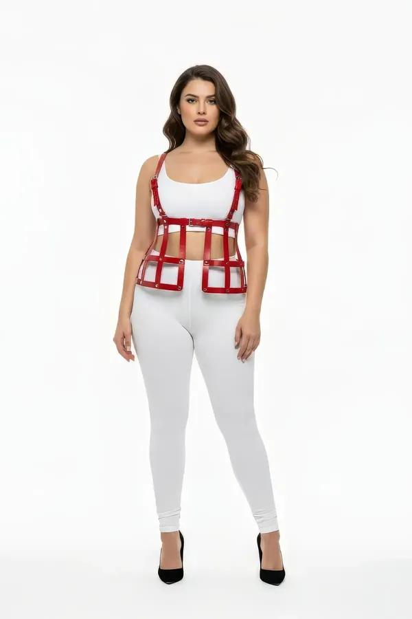 Altın tonlu perçinler ve ayarlanabilir omuz askılı kırmızı vegan deri kafes underbust harness yelek üstü, beyaz crop üzerine giyilmiş