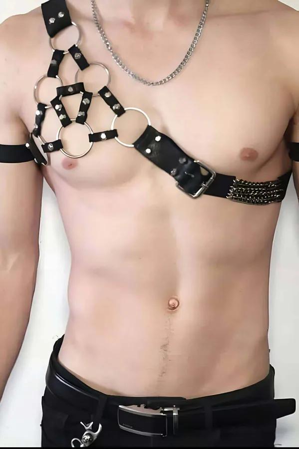 siyah suni deri asimetrik göğüs harness, sol omuzda beş gümüş O-halka ve altın zincir aksesuar paneli