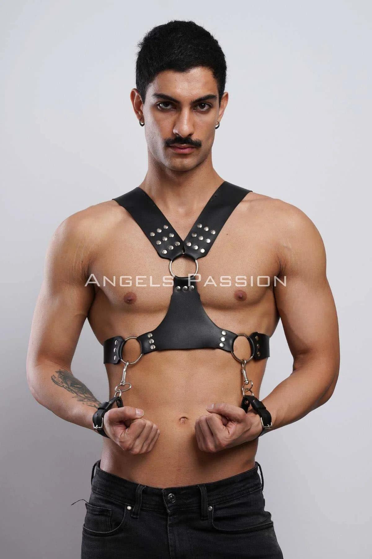 Üç gümüş O-halka ve çıkarılabilir bilek kelepçeleriyle siyah suni deri zımbalı göğüs harness, erkek model üzerinde